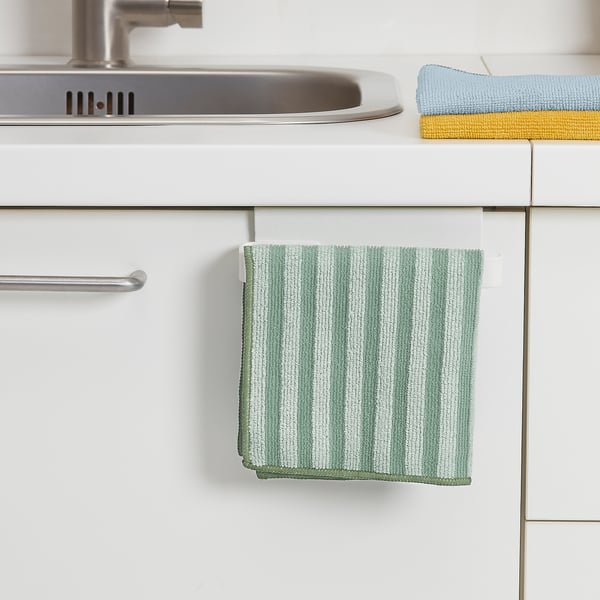 A striped green and white kitchen cloth hangs from a white rail under a sink. The absorbent microfibre cloth is used for cleaning and drying.