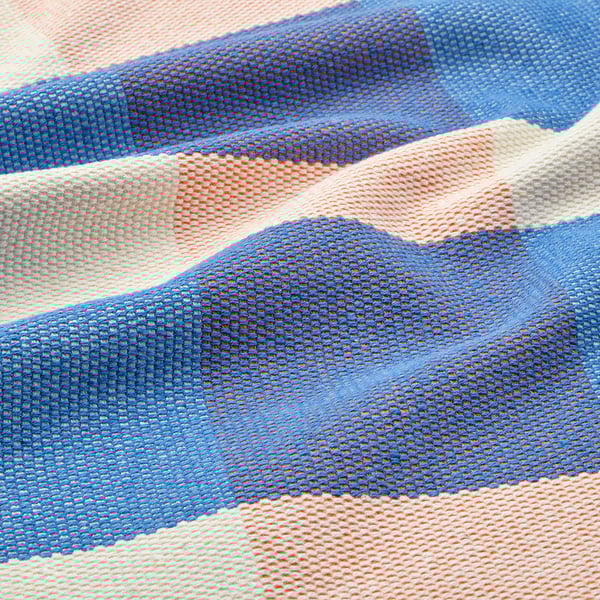 A colourful woven placemat with blue, orange, and white stripes.
