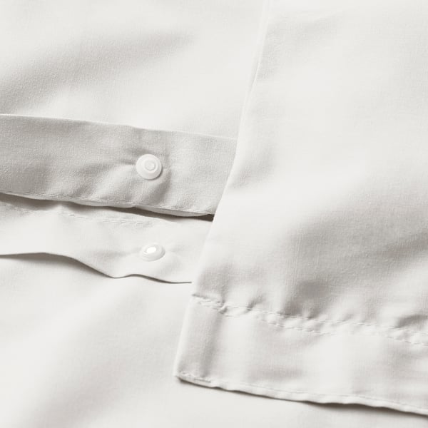 Close-up of white duvet with visible button closure, showcasing smooth fabric and neat stitching.