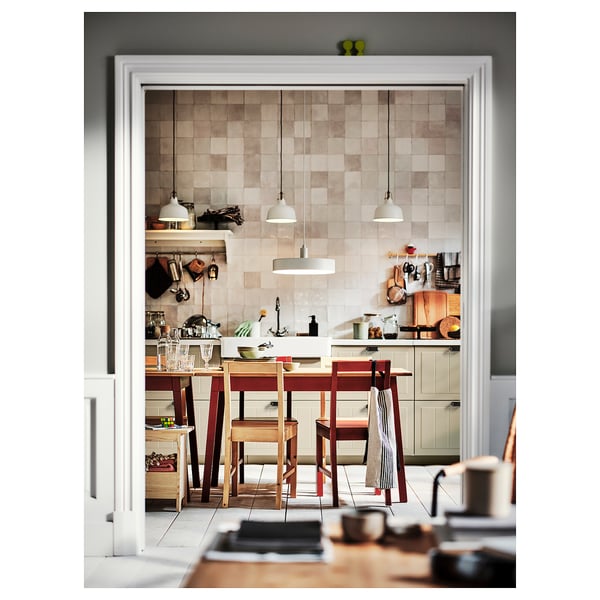 Modern kitchen with wooden dining table and chairs, tiled backsplash, hanging lamps, and various cooking utensils.