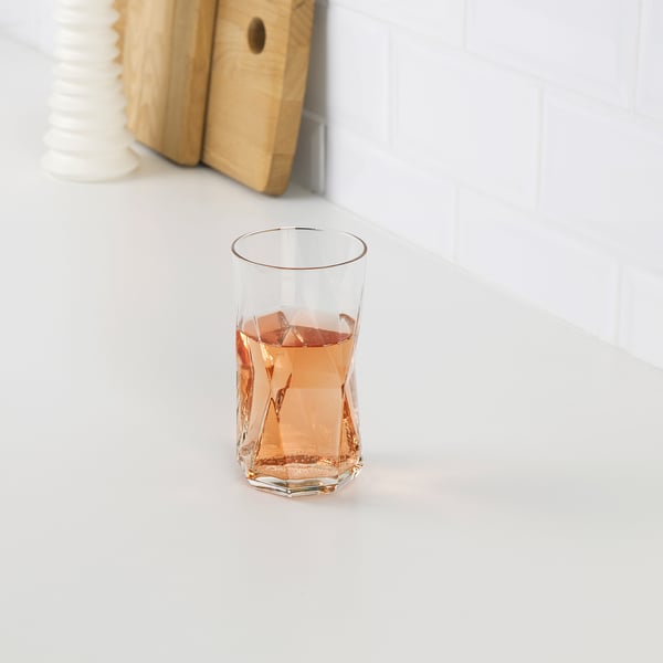 A glass of pinkish liquid with ice, showcasing PLANERAs sleek, faceted design.