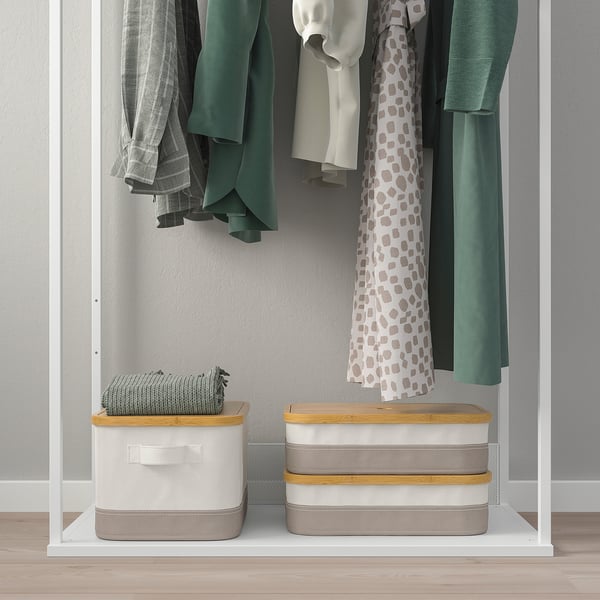 Closed closet showing hangers with coats, below are two storage boxes and a folded blanket.