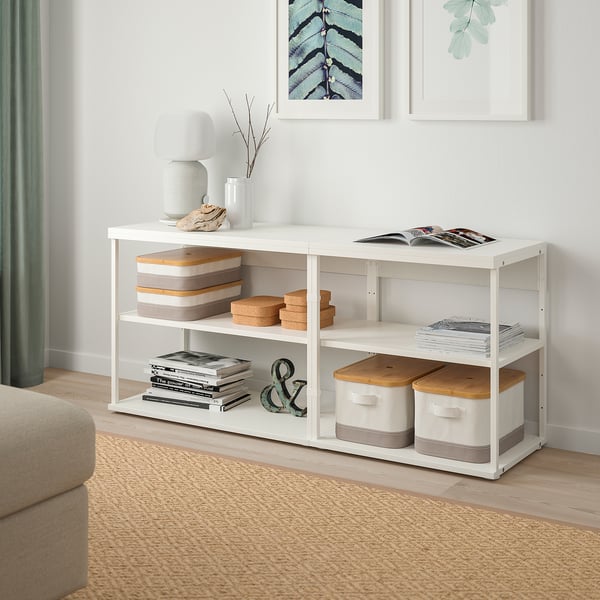 White PLATSA storage unit with shelves, holding books and decor. Versatile, space-efficient, against wall with art and rug.