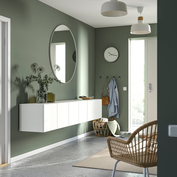 Modern entry: green walls, PLATSA storage, mirror, and chair. Minimalist decor with clock and rug.