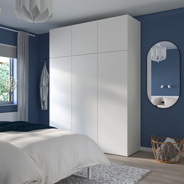 A modern blue bedroom with a large white PLATSA wardrobe reaching the ceiling.