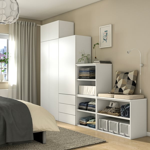 Modern bedroom with white PLATSA storage, grey walls, bed, pillows, rug, and natural light.