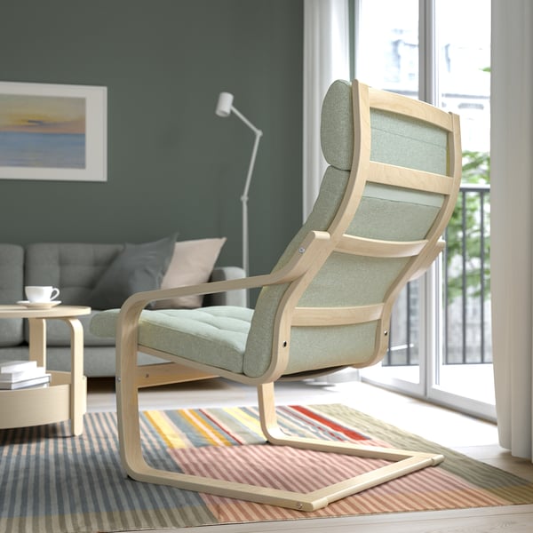Green cushioned armchair by window, with rug and side table.