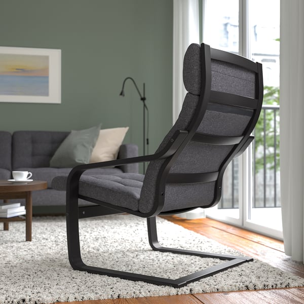 A modern living room with a grey POÄNG armchair, providing neck support and comfort, besides a couch and table.