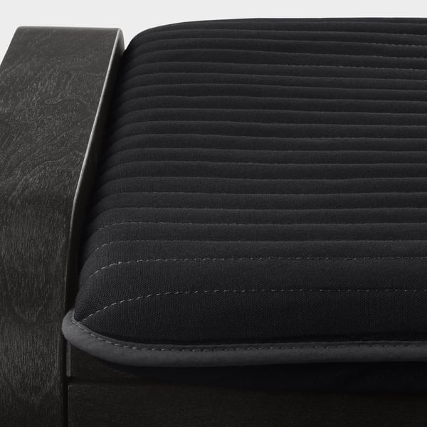 Close-up of black poang footstool, showcasing its textured, quilted surface and sturdy wooden frame.