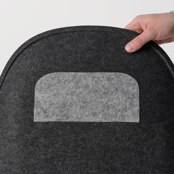 Hand holding soft, black PYNTEN seat pad with white anti-slip patch, designed for eldberget and loberget chairs.
