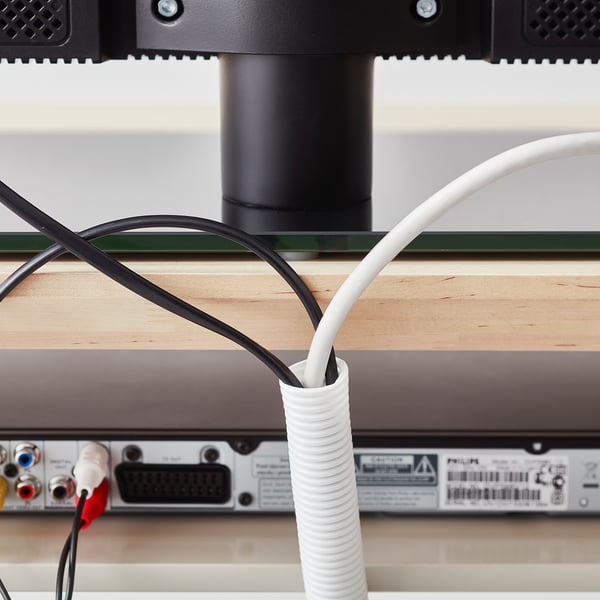 White cable organiser wraps around cords beneath a wooden desk, keeping them tidy and preventing clutter.