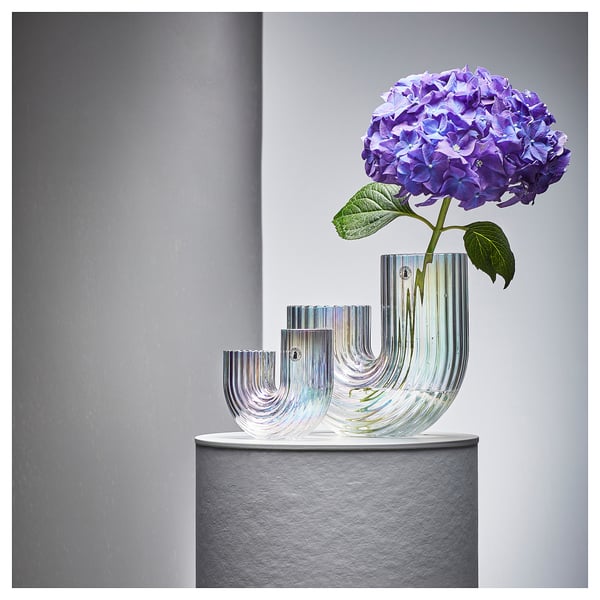 Glass vase RÄFFELBJÖRK with rainbow design by lisa hilland, holding purple hydrangea on grey pedestal.