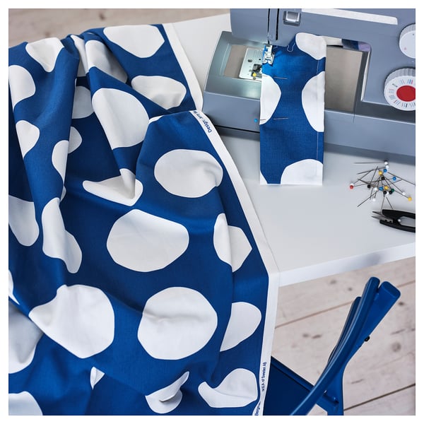 Blue fabric with white dots on sewing machine, ready for crafting.