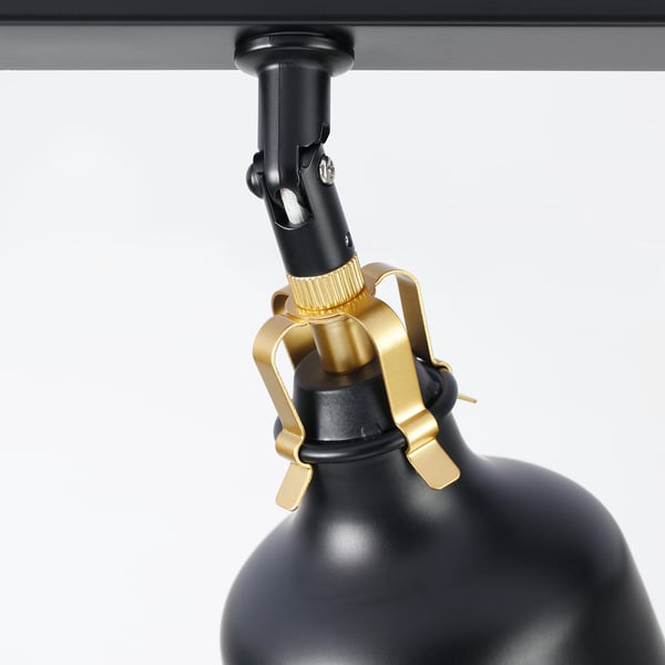Black and gold metal lamp assembly with adjustable spotlight, mounted on a dark ceiling.
