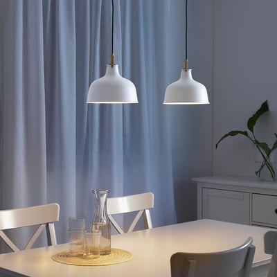 Pendant lamps above dining table with carafe. Blue curtains let in light.