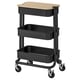 An ikea RÅSKOG trolley in black with a bamboo lid, featuring three shelves and four wheels for easy mobility.