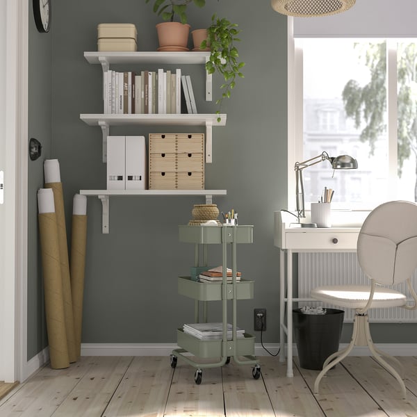 Green RÅSKOG trolley with 3 shelves, fits tight spaces, near desk and chair.