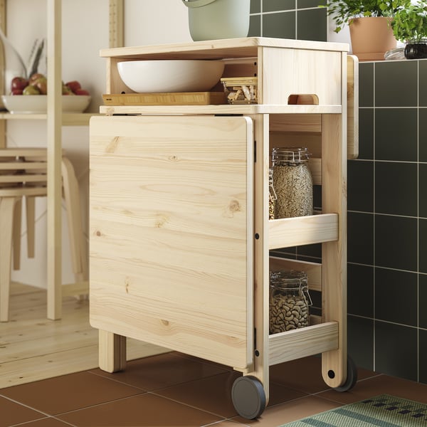 Light wooden kitchen cart with shelves and wheels, holding jars and bowls.