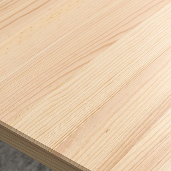 Close-up of smooth, light-colored wooden surface, showing fine grain texture and polished finish.