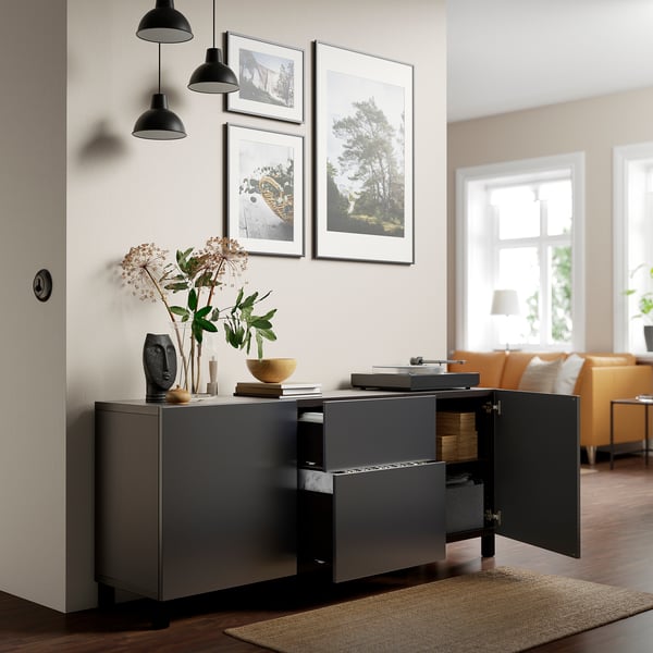 Contemporary storage cabinet with open doors revealing organised items, including a record player on top and decorative plants beside it.