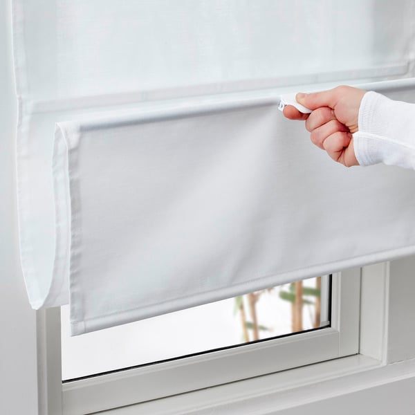 Hand raises RINGBLOMMA blind to reveal window, cordless magnetic shade.