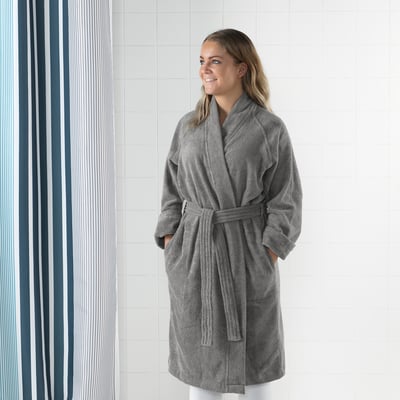 A person stands comforted in a grey bathrobe with pockets and adjustable belt.