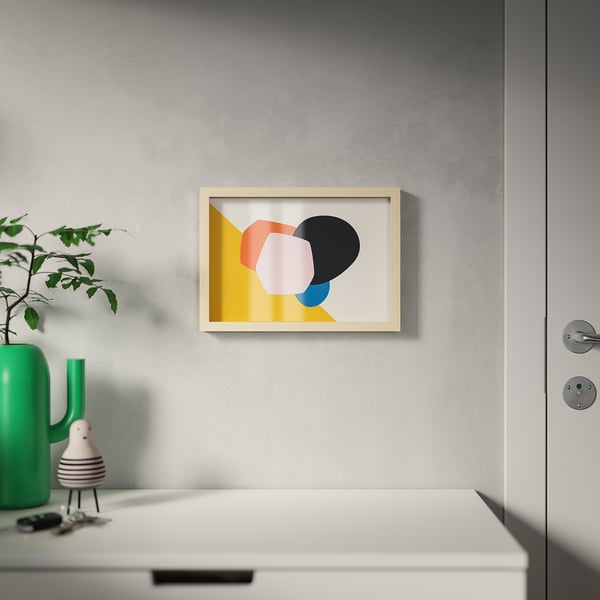 Modern art print on grey wall above white cabinet with plant.