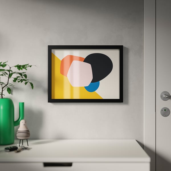 A modern framed picture hangs on a wall. The frame is adjustable for different picture sizes. A green vase with a plant is on a nearby table.