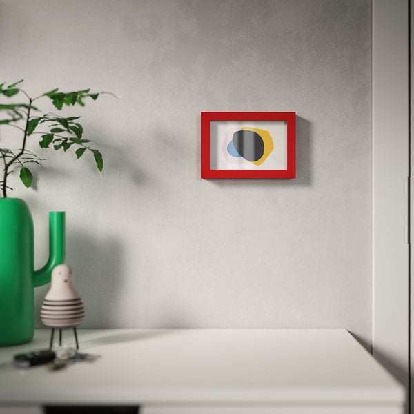 Red picture frame on textured wall, showcasing abstract art. With green plant, can hang or stand.