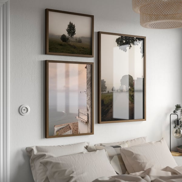 Three RÖDALM frames above bed with nature photos, middle frame reflects room.