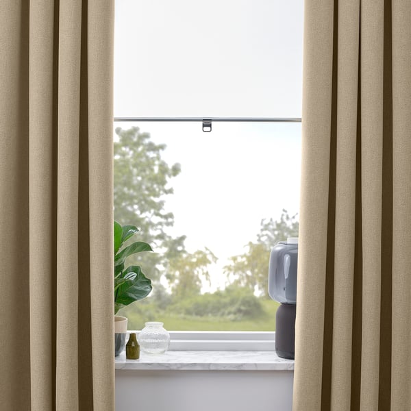 Beige curtains frame a green plant and vases on windowsill, offering privacy.