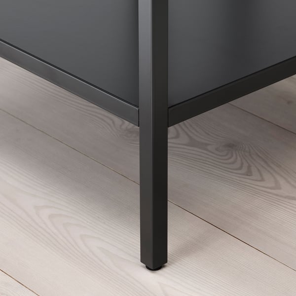 Close-up of modern cabinet leg. Dark metal with slight sheen, sturdy build, resting on stylish wood floor.