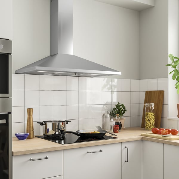 Modern kitchen with RYTMISK stainless hood, white cabinets, wooden countertop, stove with pots, and various ingredients.