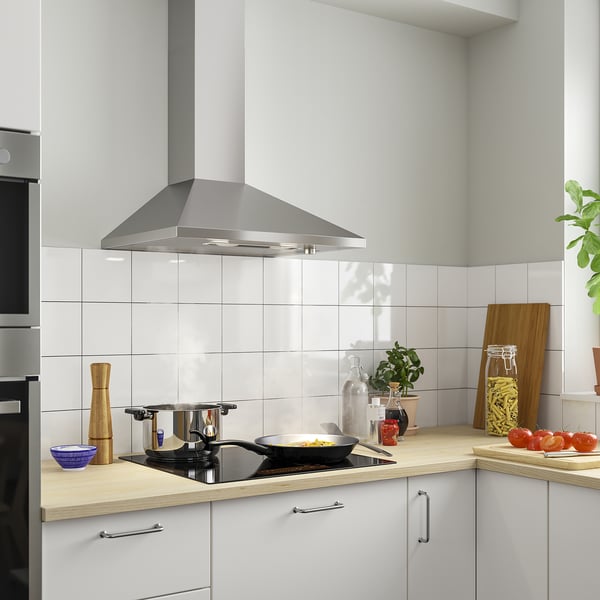 Modern kitchen with stainless steel range hood. White cabinets, wooden countertops, cooking items.