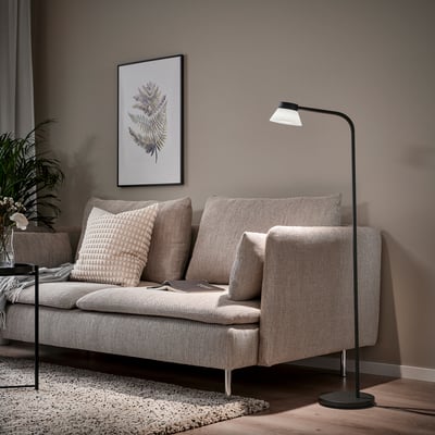 Modern living room with SAMBORD floor lamp, beige sofa, and plant poster. Lamp beside sofa provides reading light.