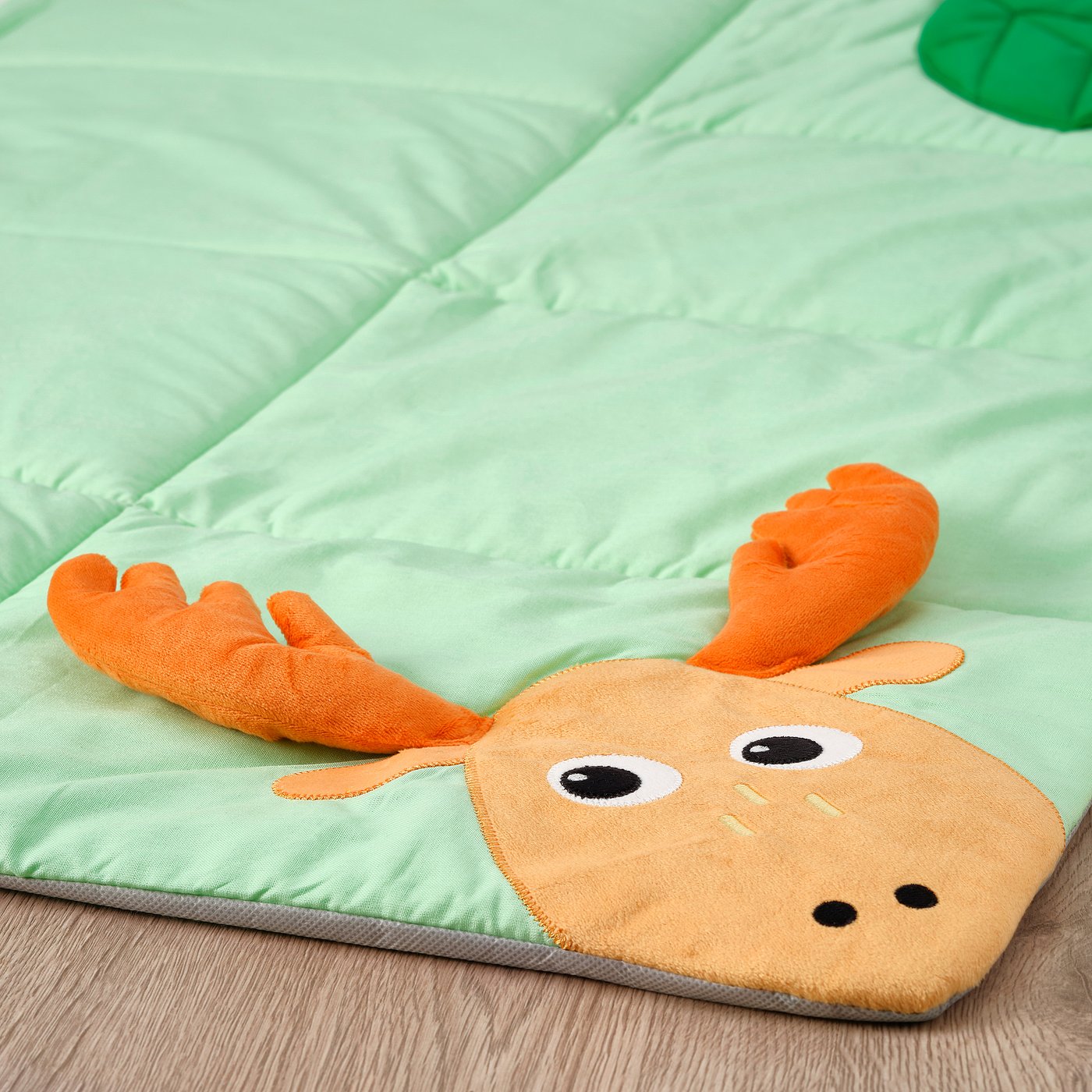 A plush mat featuring a cartoon moose, designed for babies to play on, showing vibrant colours and soft textures.