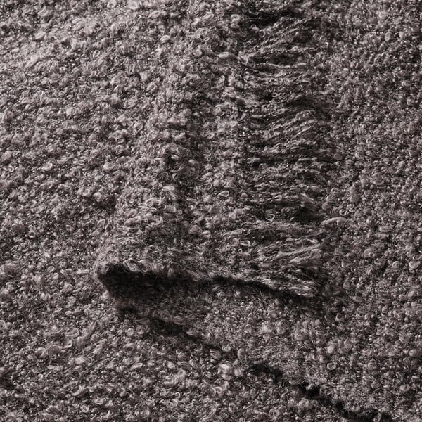 Close-up of a cosy grey crinkle-knit throw with soft, fringed edges.