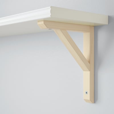 Light wooden shelf bracket mounted on wall, holding white shelf.