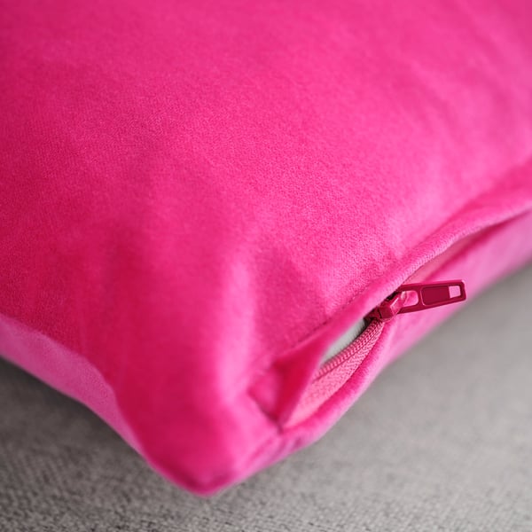 Close-up of smooth, bright pink velvet cushion cover with a zip pull, showcasing quality texture and finish.