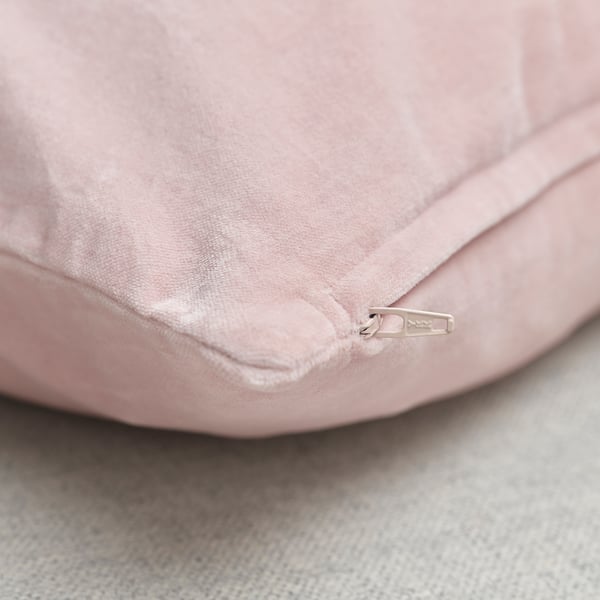 Close-up of velvet cushion, smooth fabric, visible zip closure.