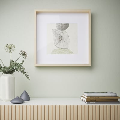 Framed abstract art on green wall, with shelf holding vase and books.