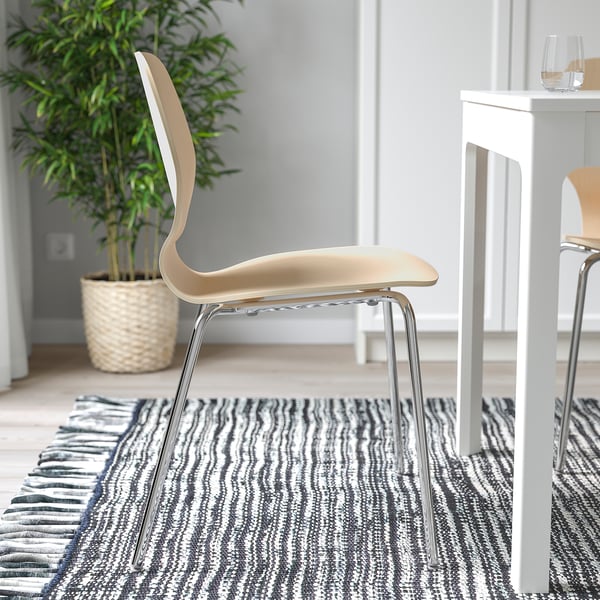 Modern chair with curved seat, chrome legs, and small table with wine glass. Set on a striped rug.