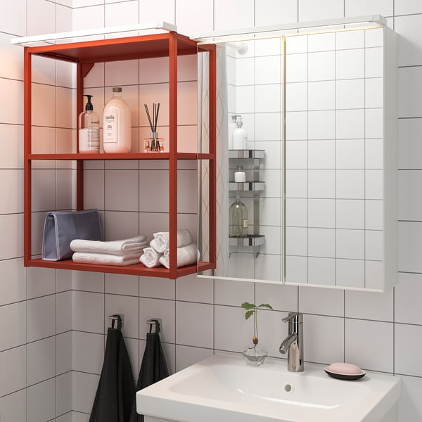 Modern bathroom with orange shelves displaying toiletries, towels, and a wall-mounted sink with led lighting.
