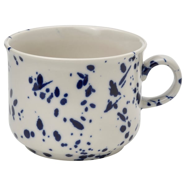 A white mug with blue splatter patterns, made of stoneware. It a sturdy handle and a speckled design, suitable for various settings.
