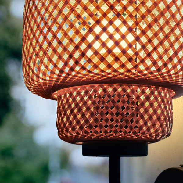 Hand-braided bamboo wall lamp with intricate weave, casting warm, soft light, mounted on a sleek base.