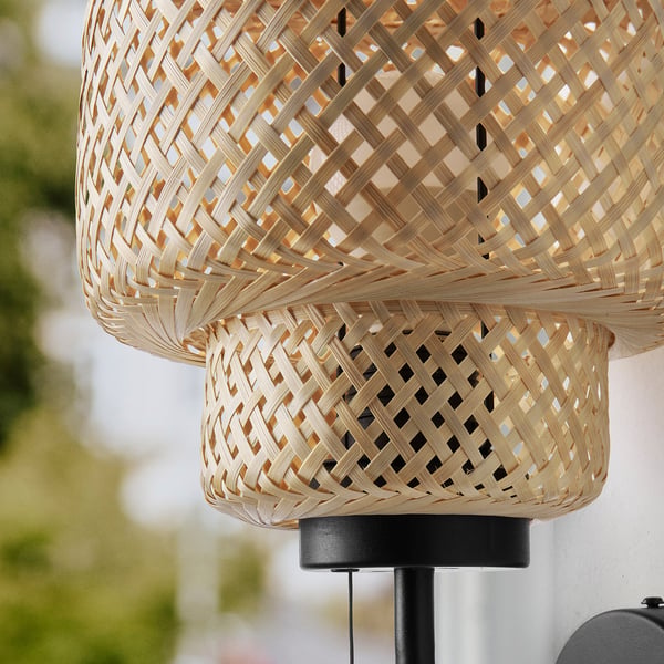 Hand-braided bamboo wall lamp, warm glowing light, natural material, craftsmanship evident.