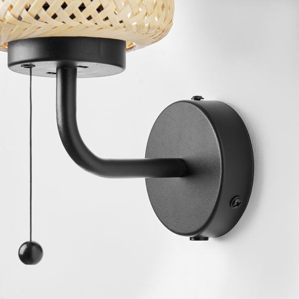 Bamboo wall lamp with black arm, pull cord, natural/modern design on white wall.