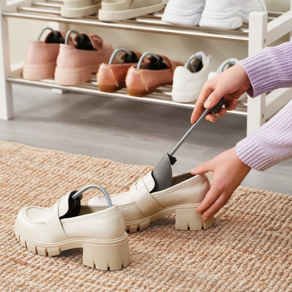 Person uses SITTPINNE shoe shapers to maintain shoe shape, useful for hallways or wardrobes.