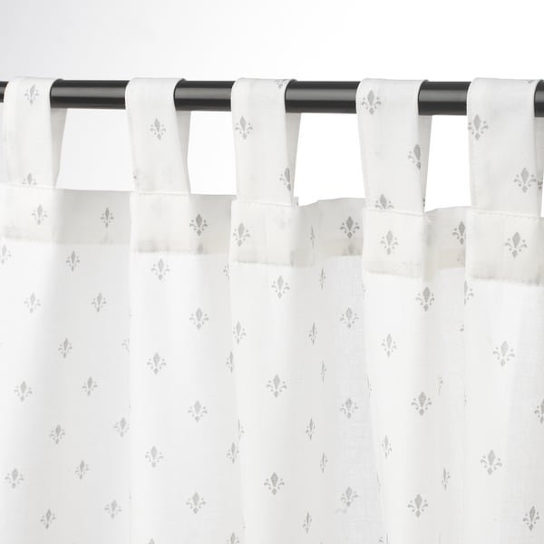 Sheer floral curtains on black rod with tab headings, allowing privacy and light.