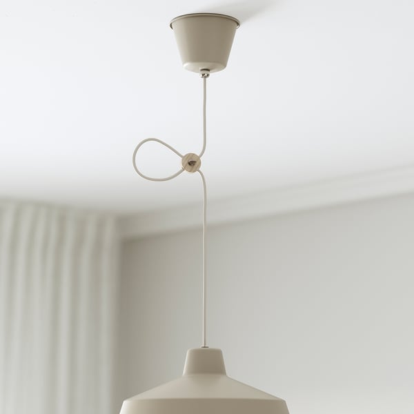 A beige pendant lamp hangs from a ceiling with an adjustable cord, providing directed light.